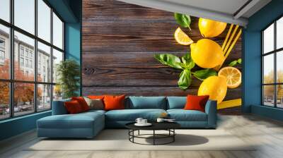 yellow whole lemons and slices, sprigs of green Basil, yellow tubes on a dark wooden background Wall mural