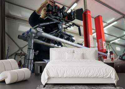 young caucasian cameraman installs a professional movie camera on a camera trolley on wheels on rails Wall mural