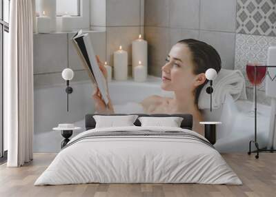 Young woman relaxes in a hot bath full of foam. Wall mural