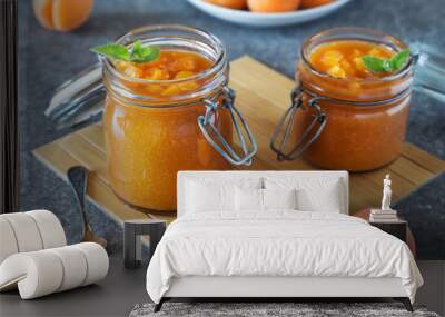 Jar of apricot jam with spoon and fruit on grey table Wall mural