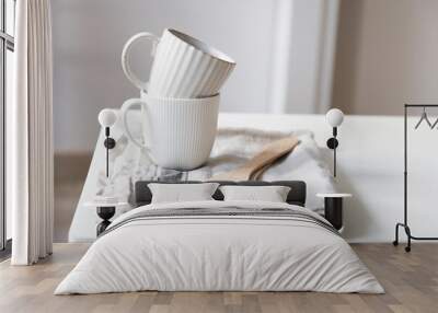 Two white mugs, a kitchen towel, a napkin and wooden frying utensils on the table. Defocus. Wall mural