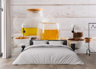 Fresh buckwheat tea in a glass and teapot and granules in a bowl on the table Wall mural