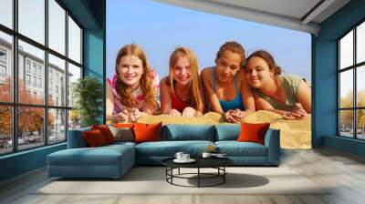 Portrait of four smiling teenage girls on a sandy beach Wall mural