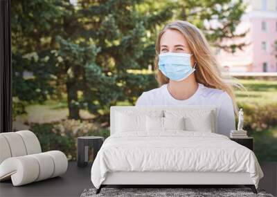 Young woman wearing protective mask outdoors. Medicine equipment. Pandemic safety concept. White t-shirt. Sick allergy or dust. Covid quarantine. Resperatory prevention Wall mural