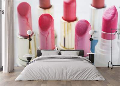 Set of colored pink lipsticks on white background. Women's cosmetics. Selective focus. Wall mural