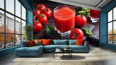 Tomato juice in glass glasses and fresh ripe tomatoes on a branch. Dark wooden background with copy space. Wall mural