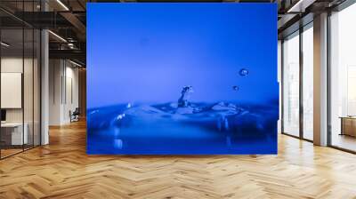 Water drop creating waves ripples and air borne water droplet Wall mural