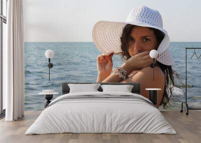 Young tanned woman posing in swimwear and hat near the sea Wall mural