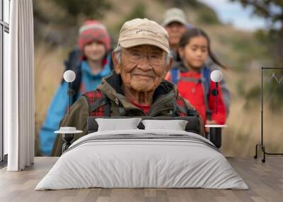 A diverse group of individuals wearing backpacks and using walking sticks hiking together in nature Wall mural