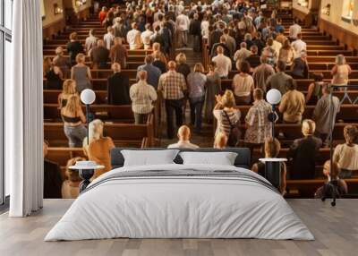 A large group of people walk into a church, filling the pews and aisles. The church has wooden pews and high ceilings, and the image captures a bright, sunny day Wall mural