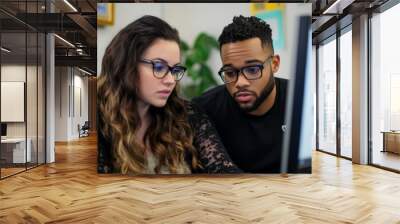 A man and woman actively participate in a virtual onboarding session, concentrating on the information displayed on their computer screen Wall mural