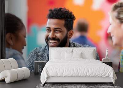 A man with a beard smiles as he talks to two women at a mental health education and support booth at a community event Wall mural