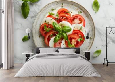 A white plate topped with vibrant sliced tomatoes and fresh basil leaves on a marble surface Wall mural