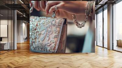 Hands elegantly hold exquisite jewelry and a decorative handbag, highlighting the allure of luxury fashion in a softly lit environment with a bokeh effect Wall mural