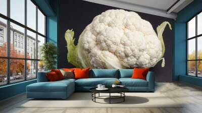 Ripe cauliflower with green leaves on dark background Wall mural