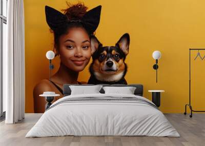 A young woman with dark skin and her corgi pose together for a cheerful photo in front of a bright yellow background Wall mural