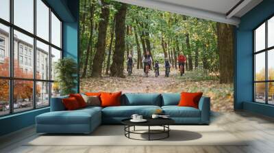 parents and kids cycling on forest trail. Young family cycling in autumn park. Family mountain biking on forest. Theme family active sports outdoor recreation. Family Cycling Through Fall Woodland Wall mural