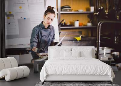 Subject profession and cooking pastry. young Caucasian woman with tattoo of pastry chef in kitchen of restaurant preparing round chocolate candies handmade truffle in black gloves and uniform Wall mural