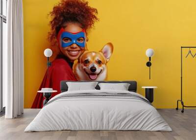 Young woman in a red cape and blue mask happily holds a corgi against a bright yellow background in a playful moment of joy Wall mural