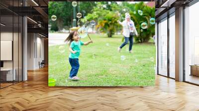 Lovely active little asian girl playing with soap bubble outdoor in the park Wall mural