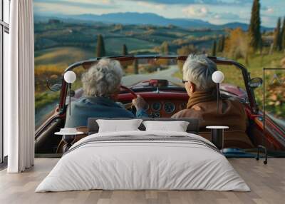 Old senior couple is driving a blue convertible car. People ride in fashionable retro cabriolet. A fun road trip. Beautiful vintage car. Summer auto travel. Happy holidays. Weekend adventure. Wall mural