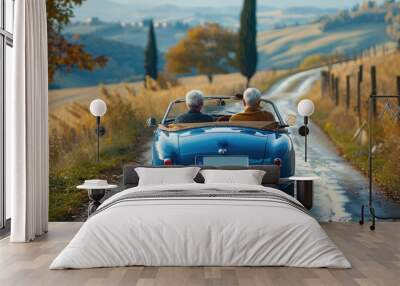 Old senior couple is driving a blue convertible car. People ride in fashionable retro cabriolet. A fun road trip. Beautiful vintage car. Summer auto travel. Happy holidays. Weekend adventure. Wall mural