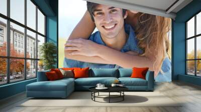 Couple, portrait and piggyback for fun in nature, love and care in relationship on outdoor date. Happy people, embrace and carrying on holiday or vacation, bonding and laughing on adventure at park Wall mural