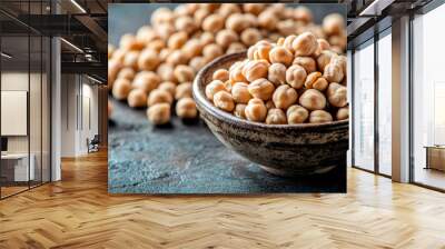 A bowl or spoon filled with dried chickpeas sits on a table.  Behind it, there's a pile of chickpeas. Wall mural