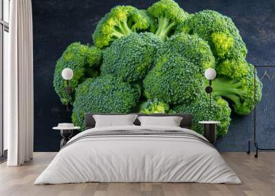 A close-up shot shows a bunch of fresh, green broccoli on a dark table. Broccoli is a healthy vegetable packed with vitamins, making it a great choice for a healthy diet. Wall mural