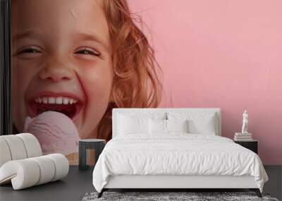 A close-up photo of a young girl with curly hair, enjoying a scoop of ice cream. She is smiling broadly, with a pink background behind her Wall mural