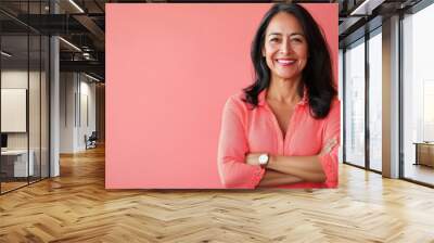 A middle-aged Hispanic woman stands confidently with her arms crossed, smiling joyfully. The vibrant background adds to the positive energy of her expression Wall mural