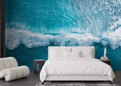 An aerial perspective captures a powerful ocean wave breaking against the horizon, with a clear blue sky above Wall mural