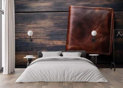 A brown leather wallet sits on a rustic wooden background. Wall mural