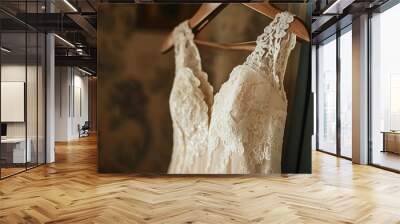 Closeup of a beautiful, lace wedding dress hanging on a wooden hanger. Wall mural