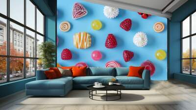 Colorful candies and raspberries on a blue background. Wall mural