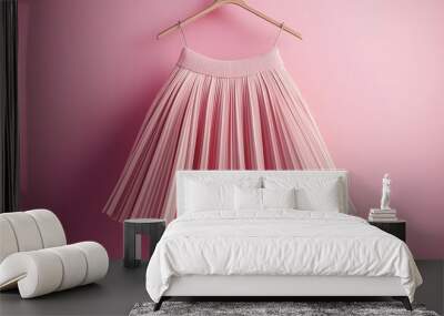 Pink pleated skirt hanging on wooden hanger against a pink background. Wall mural