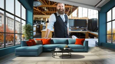 Male business owner with facial hair beard standing proudly at his work desk with paperwork  Wall mural