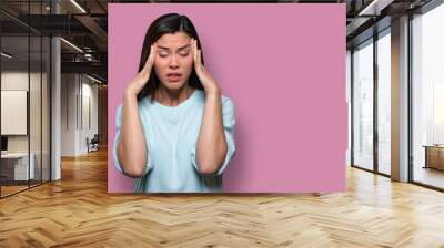 Woman overwhelmed with stress and concern, confusion and doubt, hands to head, on pink background copy space Wall mural