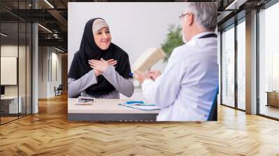 Arab woman visiting experienced doctor Wall mural