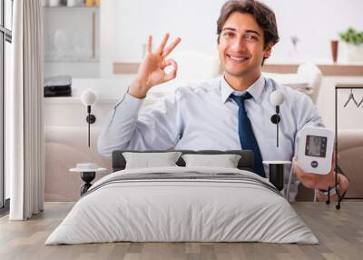 man under stress measuring his blood pressure Wall mural