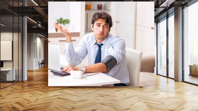 Man under stress measuring his blood pressure Wall mural