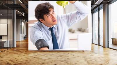 Man under stress measuring his blood pressure Wall mural