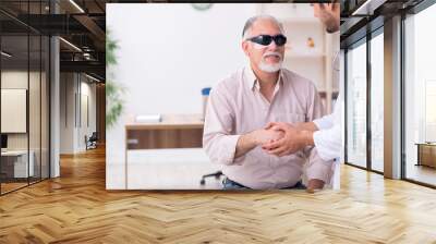 Old blind man visiting young male doctor Wall mural