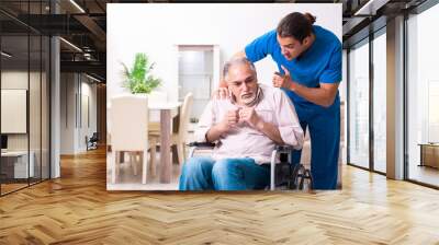 Old man in wheel-chair and young bad caregiver indoors Wall mural