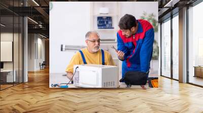 Two male repairmen working at workshop Wall mural