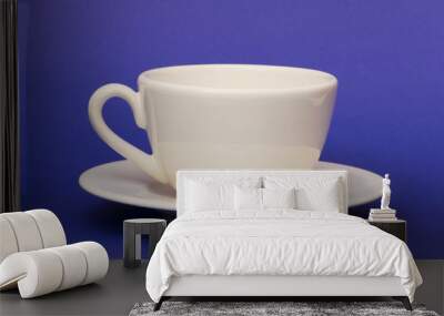 White cup isolated on the blue background Wall mural