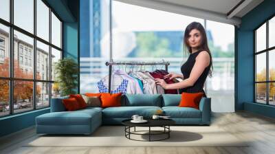 Woman choosing clothing in shop Wall mural