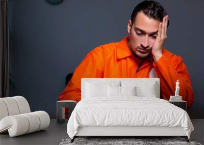 Young convict man sitting in dark room Wall mural