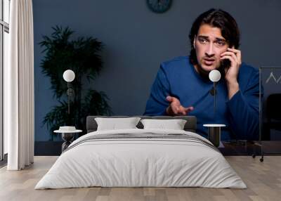 Young convict man sitting in dark room Wall mural