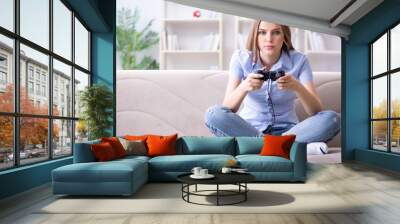 Young female student playing games at home Wall mural